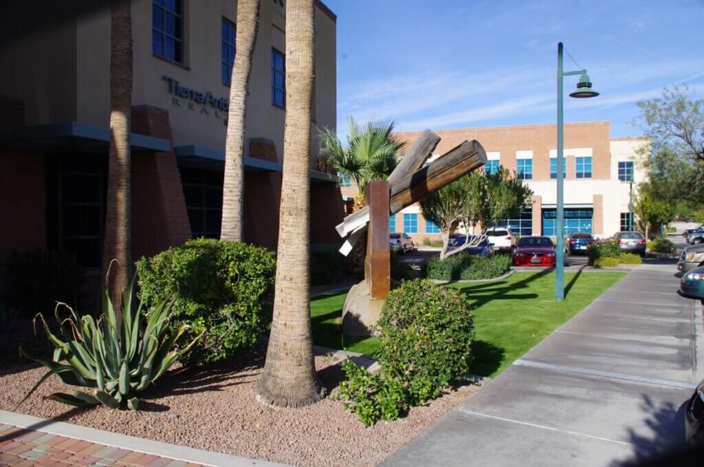 Tucson landscapers maintaining lush greenery, palm trees, and desert plants around a professionally landscaped commercial property.
